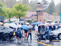 Parents hold umbrellas to pick up their children from school after Typhoon Kong-Rey brings strong winds and heavy rain in Shanghai, China, o...