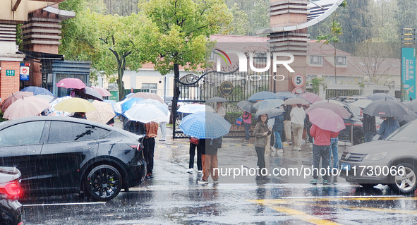 Parents hold umbrellas to pick up their children from school after Typhoon Kong-Rey brings strong winds and heavy rain in Shanghai, China, o...