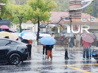 Parents hold umbrellas to pick up their children from school after Typhoon Kong-Rey brings strong winds and heavy rain in Shanghai, China, o...