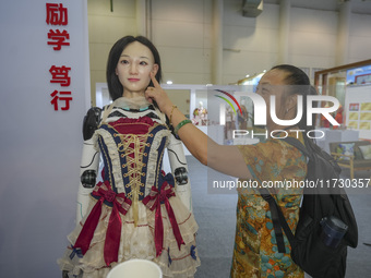 A spectator touches a silicone material to simulate the face of an embodied robot in Xiamen, China, on November 1, 2024. (