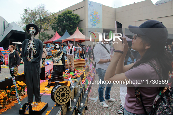 A woman takes a photo of a Day of the Dead offering during the Twenty-seventh edition of the University Day of the Dead Festival ''Mega Ofre...