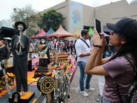 A woman takes a photo of a Day of the Dead offering during the Twenty-seventh edition of the University Day of the Dead Festival ''Mega Ofre...