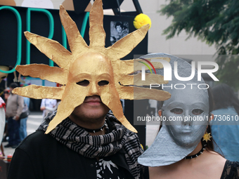 A couple wearing Sun and Moon masks is seen during the Twenty-seventh Edition of the University Day of the Dead Festival ''Mega Ofrenda UNAM...