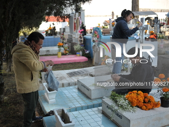 Relatives decorate the graves of their loved ones with cempasuchil flowers and hold a vigil at the Municipal Cemetery of Amealco de Bonfil....