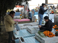 Relatives decorate the graves of their loved ones with cempasuchil flowers and hold a vigil at the Municipal Cemetery of Amealco de Bonfil....