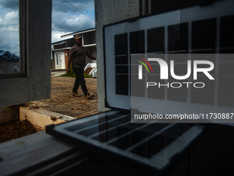 A worker, Wahyu, 31, repairs a water installation with the foreground of an emergency solar power plant at a house in the new subsidized set...