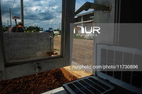 A worker, Wahyu, 31, repairs a water installation with the foreground of an emergency solar power plant at a house in the new subsidized set...