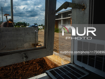 A worker, Wahyu, 31, repairs a water installation with the foreground of an emergency solar power plant at a house in the new subsidized set...