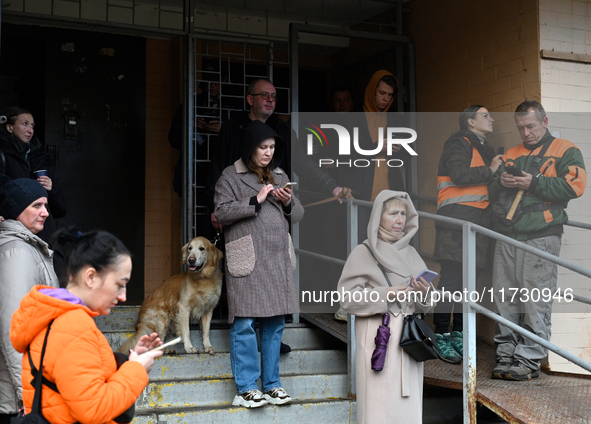 People stand at an entrance to a 16-storey residential building in the Sviatoshynskyi district damaged by falling Russian drone debris in Ky...