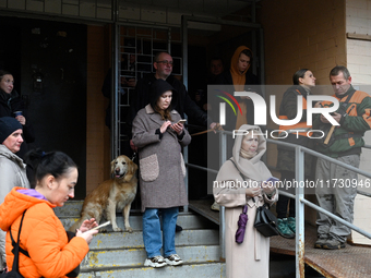 People stand at an entrance to a 16-storey residential building in the Sviatoshynskyi district damaged by falling Russian drone debris in Ky...