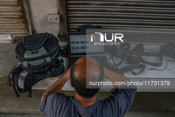 A photojournalist works near the site of a gun battle between suspected militants and security forces in Srinagar, Jammu and Kashmir, on Nov...