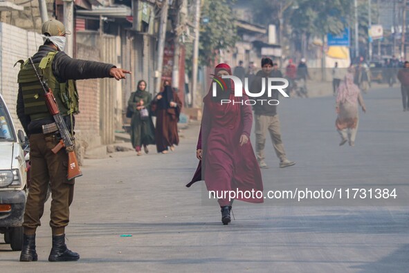 An Indian policeman gestures towards a civilian near the site of a gunbattle between suspected militants and security forces in Srinagar, Ja...