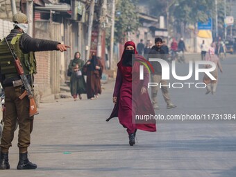 An Indian policeman gestures towards a civilian near the site of a gunbattle between suspected militants and security forces in Srinagar, Ja...