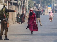 An Indian policeman gestures towards a civilian near the site of a gunbattle between suspected militants and security forces in Srinagar, Ja...