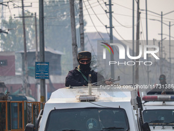 An Indian security personnel stands alert atop an armored vehicle during a gun battle between suspected militants and security forces in Sri...