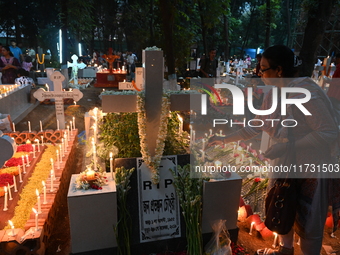 Christian devotees light candles on the graves of relatives during the celebrations of All Souls Day in a cemetery at Wari Cemetery of Holy...