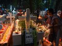 Christian devotees light candles on the graves of relatives during the celebrations of All Souls Day in a cemetery at Wari Cemetery of Holy...