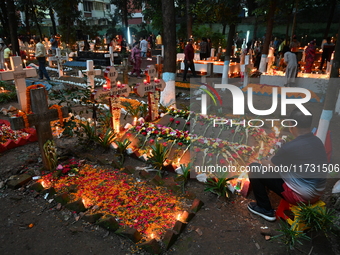 Christian devotees light candles on the graves of relatives during the celebrations of All Souls Day in a cemetery at Wari Cemetery of Holy...