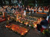 Christian devotees light candles on the graves of relatives during the celebrations of All Souls Day in a cemetery at Wari Cemetery of Holy...