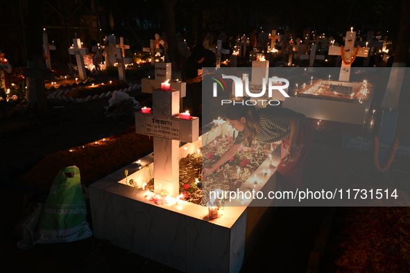 Christian devotees light candles on the graves of relatives during the celebrations of All Souls Day in a cemetery at Wari Cemetery of Holy...