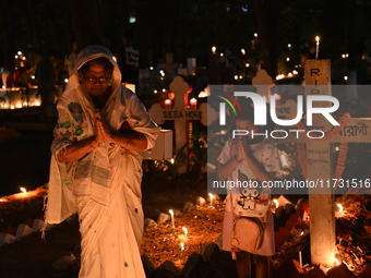 Christian devotees light candles on the graves of relatives during the celebrations of All Souls Day in a cemetery at Wari Cemetery of Holy...