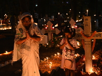 Christian devotees light candles on the graves of relatives during the celebrations of All Souls Day in a cemetery at Wari Cemetery of Holy...