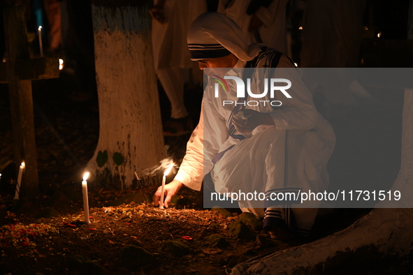 Christian devotees light candles on the graves of relatives during the celebrations of All Souls Day in a cemetery at Wari Cemetery of Holy...