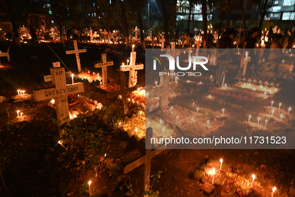 Christian devotees light candles on the graves of relatives during the celebrations of All Souls Day in a cemetery at Wari Cemetery of Holy...