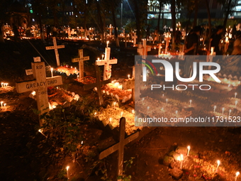 Christian devotees light candles on the graves of relatives during the celebrations of All Souls Day in a cemetery at Wari Cemetery of Holy...