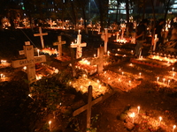 Christian devotees light candles on the graves of relatives during the celebrations of All Souls Day in a cemetery at Wari Cemetery of Holy...