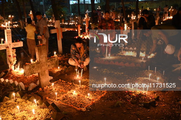 Christian devotees light candles on the graves of relatives during the celebrations of All Souls Day in a cemetery at Wari Cemetery of Holy...