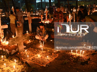 Christian devotees light candles on the graves of relatives during the celebrations of All Souls Day in a cemetery at Wari Cemetery of Holy...