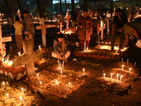 Christian devotees light candles on the graves of relatives during the celebrations of All Souls Day in a cemetery at Wari Cemetery of Holy...