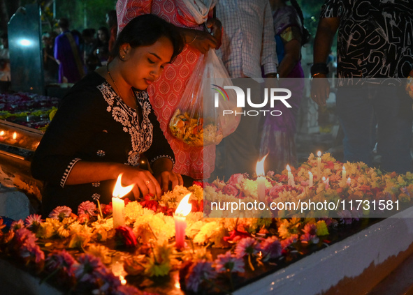 A woman lights candles at the grave of departed ones to commemorate All Souls Day at a cemetery in Hyderabad, on November 2, 2024. 