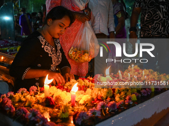 A woman lights candles at the grave of departed ones to commemorate All Souls Day at a cemetery in Hyderabad, on November 2, 2024. (