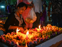 A woman lights candles at the grave of departed ones to commemorate All Souls Day at a cemetery in Hyderabad, on November 2, 2024. (