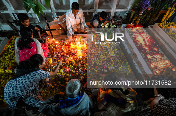 Family and friends light candles at the graves of departed ones to commemorate All Souls Day at a cemetery in Hyderabad, on November 2, 2024...