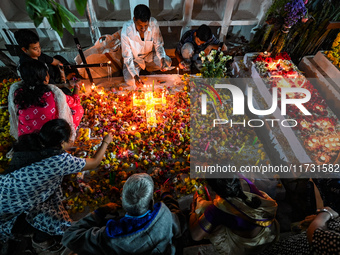 Family and friends light candles at the graves of departed ones to commemorate All Souls Day at a cemetery in Hyderabad, on November 2, 2024...