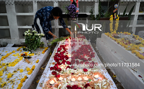 A woman lights candles at the grave of departed ones to commemorate All Souls Day at a cemetery in Hyderabad, on November 2, 2024. 