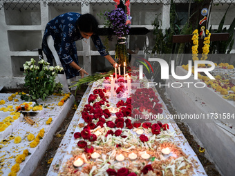 A woman lights candles at the grave of departed ones to commemorate All Souls Day at a cemetery in Hyderabad, on November 2, 2024. (