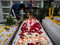 A woman lights candles at the grave of departed ones to commemorate All Souls Day at a cemetery in Hyderabad, on November 2, 2024. (