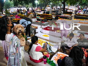 A family with a pet dog prays next to the grave of departed ones to commemorate All Souls Day at a cemetery in Hyderabad, on November 2, 202...