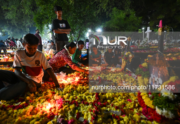 Family and friends light candles at the graves of departed ones to commemorate All Souls Day at a cemetery in Hyderabad, on November 2, 2024...