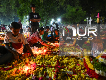 Family and friends light candles at the graves of departed ones to commemorate All Souls Day at a cemetery in Hyderabad, on November 2, 2024...