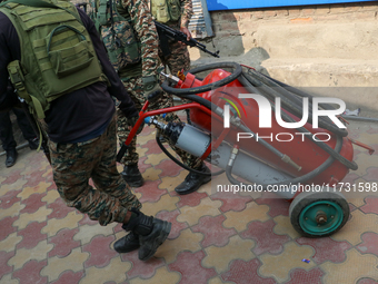 Indian paramilitary troopers carry a flamethrower as they move towards an encounter site in Srinagar, Indian Administered Kashmir, on Novemb...