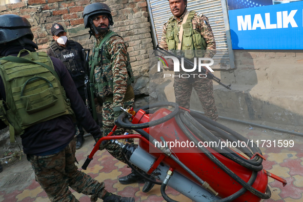 Indian paramilitary troopers carry a flamethrower as they move towards an encounter site in Srinagar, Indian Administered Kashmir, on Novemb...