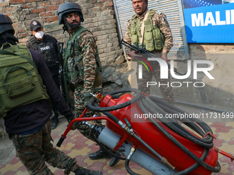 Indian paramilitary troopers carry a flamethrower as they move towards an encounter site in Srinagar, Indian Administered Kashmir, on Novemb...