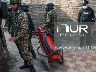 Indian paramilitary troopers carry a flamethrower as they move towards an encounter site in Srinagar, Indian Administered Kashmir, on Novemb...