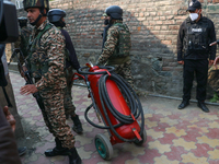 Indian paramilitary troopers carry a flamethrower as they move towards an encounter site in Srinagar, Indian Administered Kashmir, on Novemb...