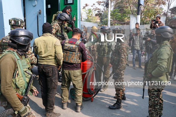 Indian paramilitary troopers carry a flamethrower as they move towards an encounter site in Srinagar, Indian Administered Kashmir, on Novemb...